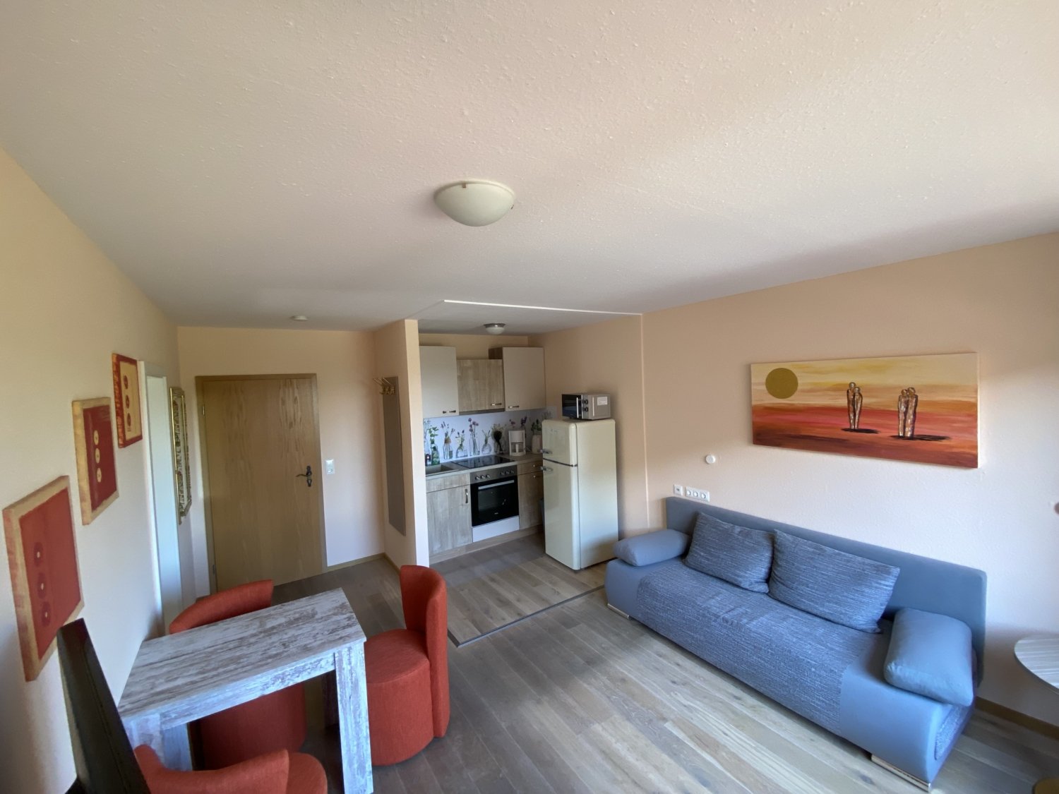 Sonnengarten_Mainaubucht_Wohnbereich Wohnbereich mit Sofa und eine Einbauküche im Hintergrund