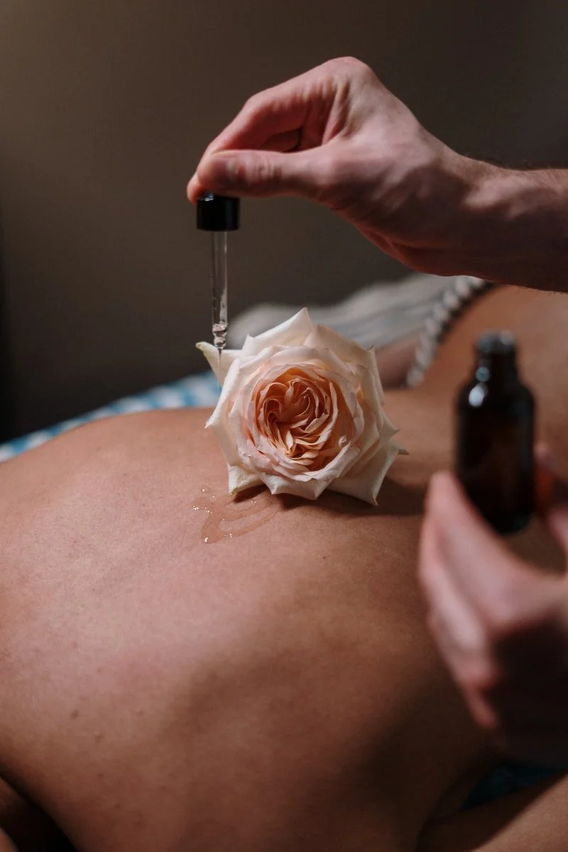 Rose und Öl auf einem nackten Rücken während einer Massage